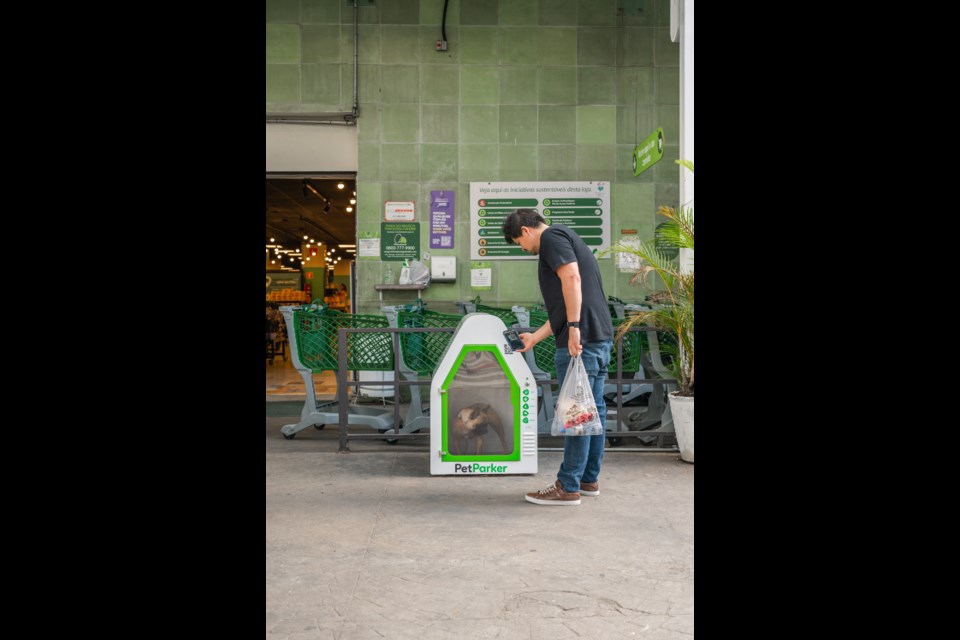 Dog in Kennel outside grocery store with owner standing beside it